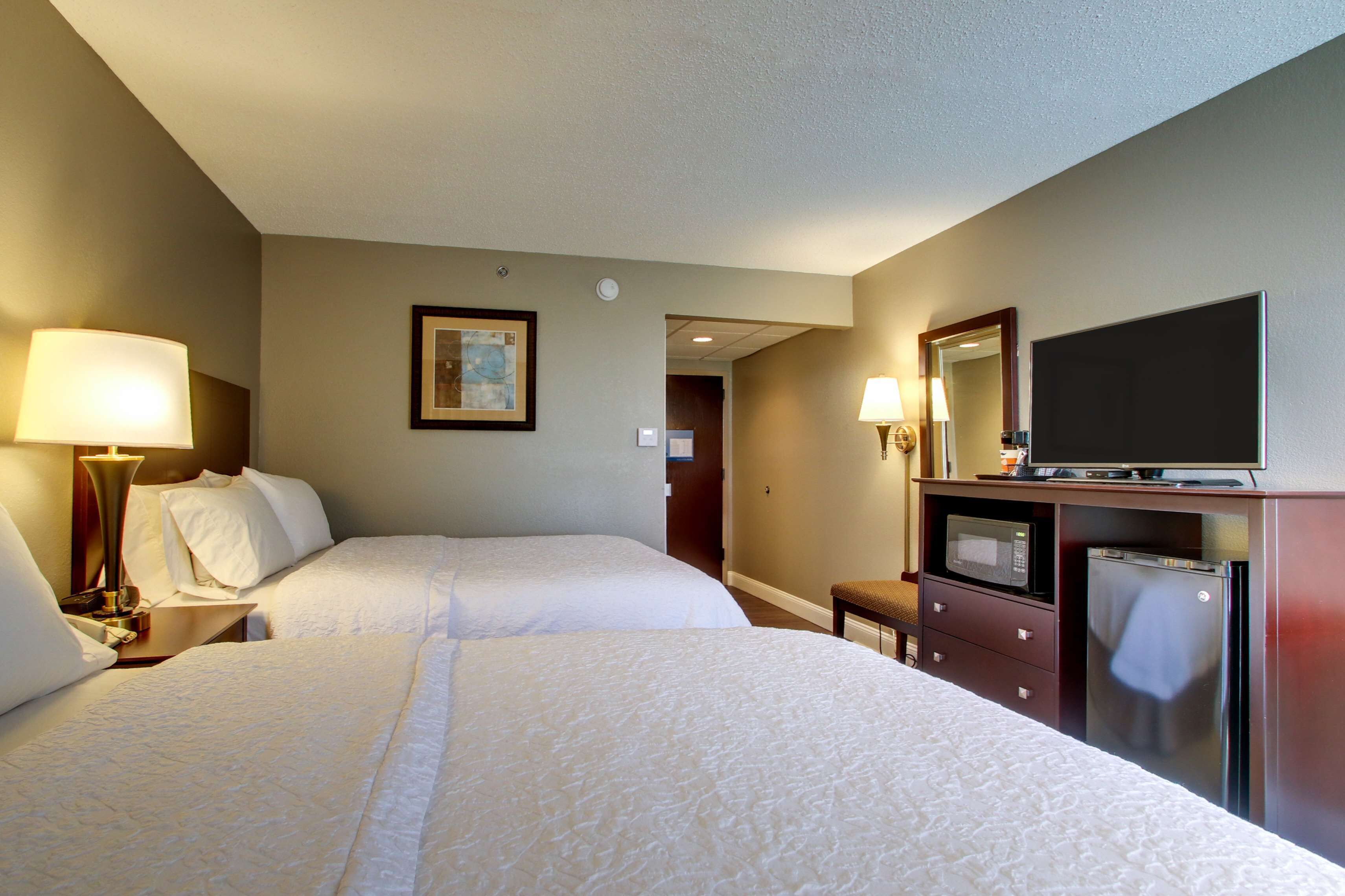 A hotel room with two beds, a television, a microwave, and a refrigerator.