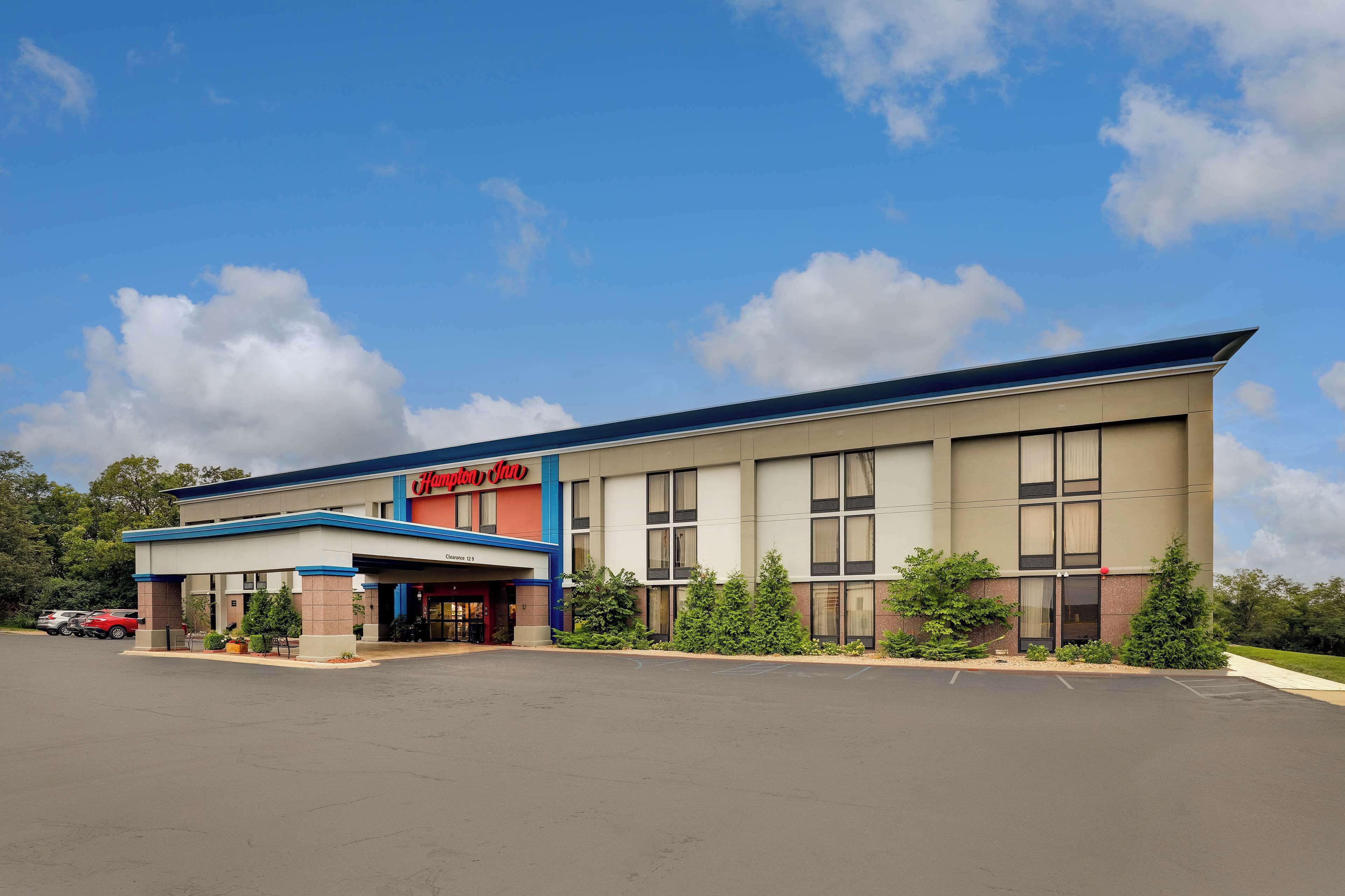 A Hampton Inn hotel with a covered entrance, parking lot, and landscaping.