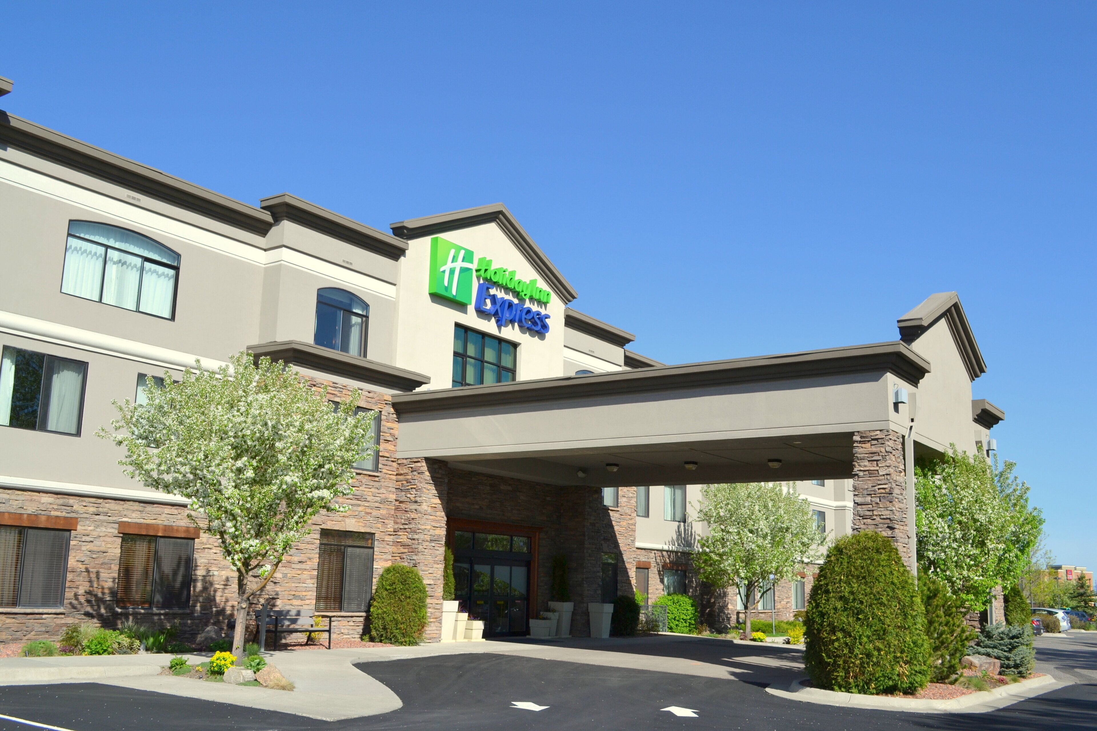 A Holiday Inn Express hotel with a covered entrance, stone facade, and landscaped surroundings.