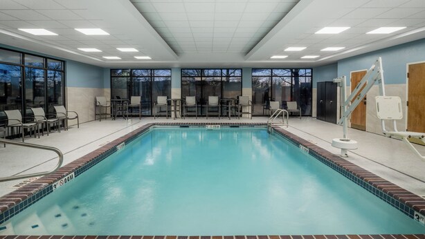 A swimming pool with clear blue water, surrounded by lounge chairs and a sunshade. - Holiday Inn Express Hotel & Suites Bozeman West by IHG (Bozeman)