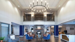 A spacious lobby with a high ceiling, a fireplace, and a reception desk. - Holiday Inn Express Hotel & Suites Bozeman West by IHG (Bozeman)