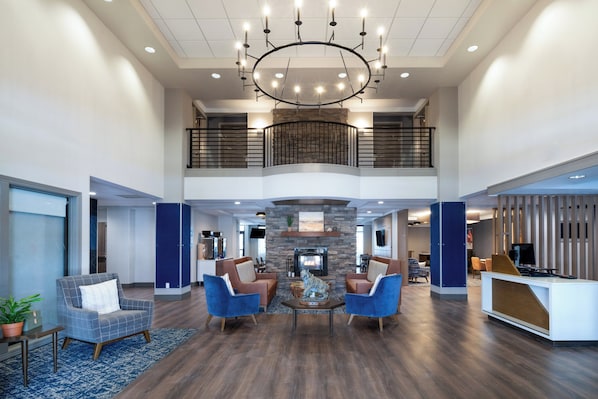 A spacious lobby with a high ceiling, a fireplace, and a reception desk. - Holiday Inn Express Hotel & Suites Bozeman West by IHG (Bozeman)