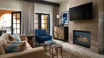 A modern living room with a sofa, armchair, and a flat-screen TV mounted on the wall.