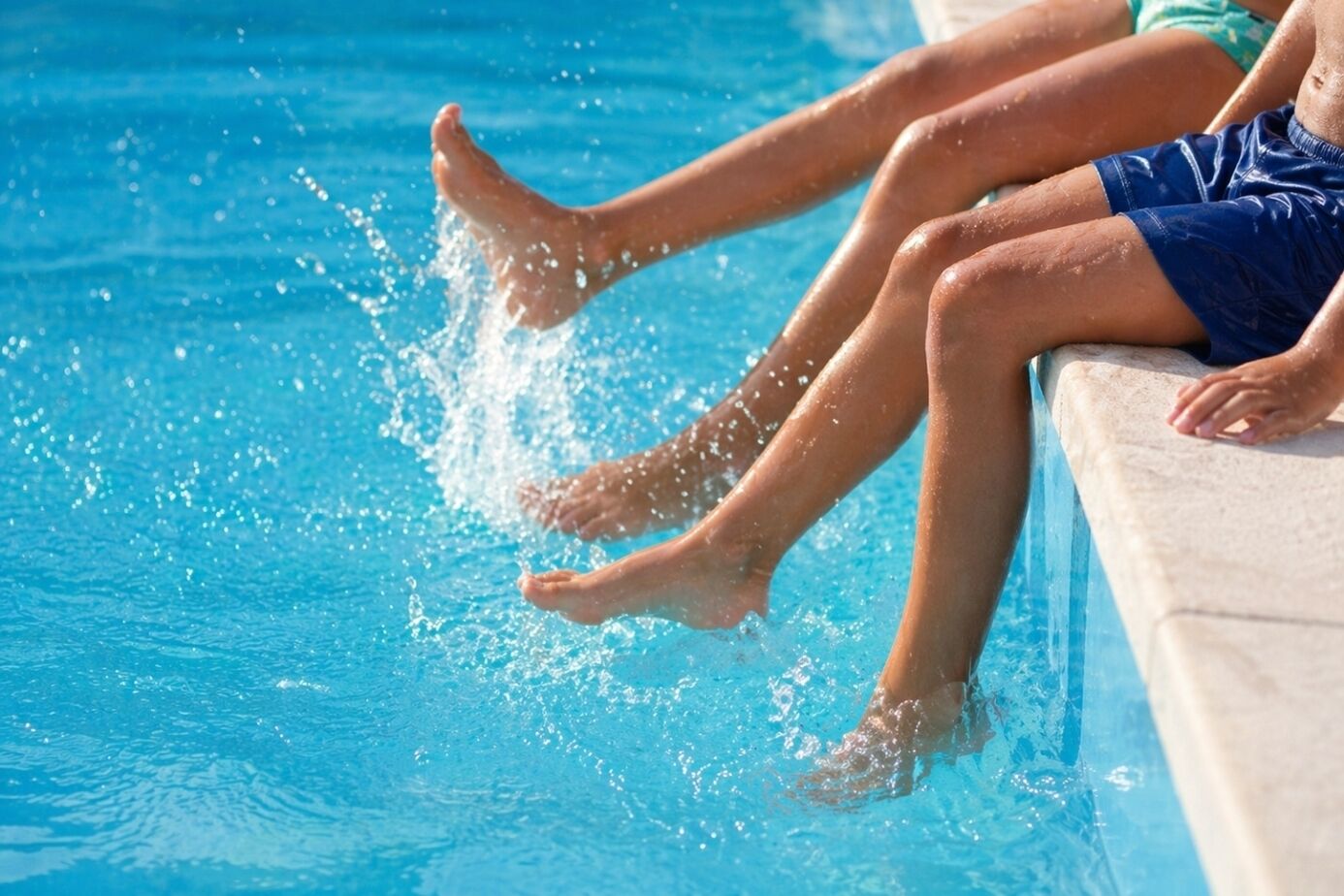 A poolside area with a clear view of the water and a person's legs resting on the edge.