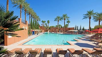 A pool area with lounge chairs and palm trees.
