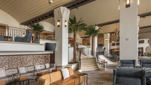 A spacious lobby with a curved leather sofa, a high ceiling, and a staircase leading to upper floors.