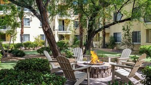 Un hogar rodeado de sillas Adirondack en un patio con un edificio al fondo.