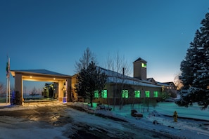 A hotel with a gas station, snow-covered landscape, and a prominent tower.