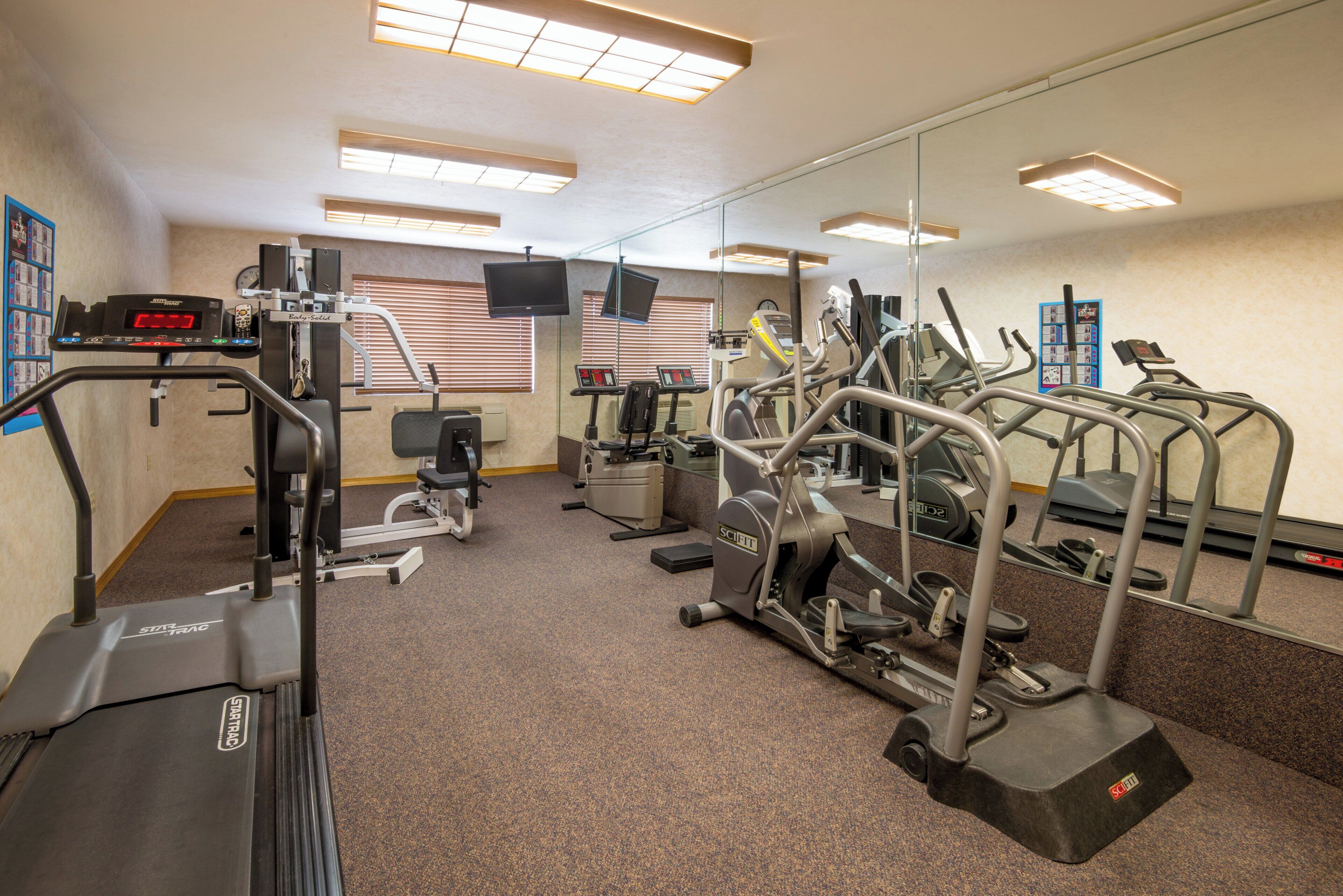 A gym with various exercise equipment, including treadmills, elliptical machines, and weight machines.