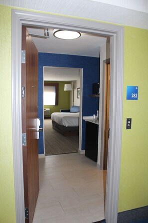 A hotel room with a bed, a desk, and a bathroom visible through an open door. - Holiday Inn Express Hotel & Suites Raton by IHG (Raton)