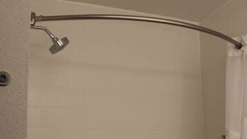 A white tiled shower with a curved showerhead and a white curtain.
