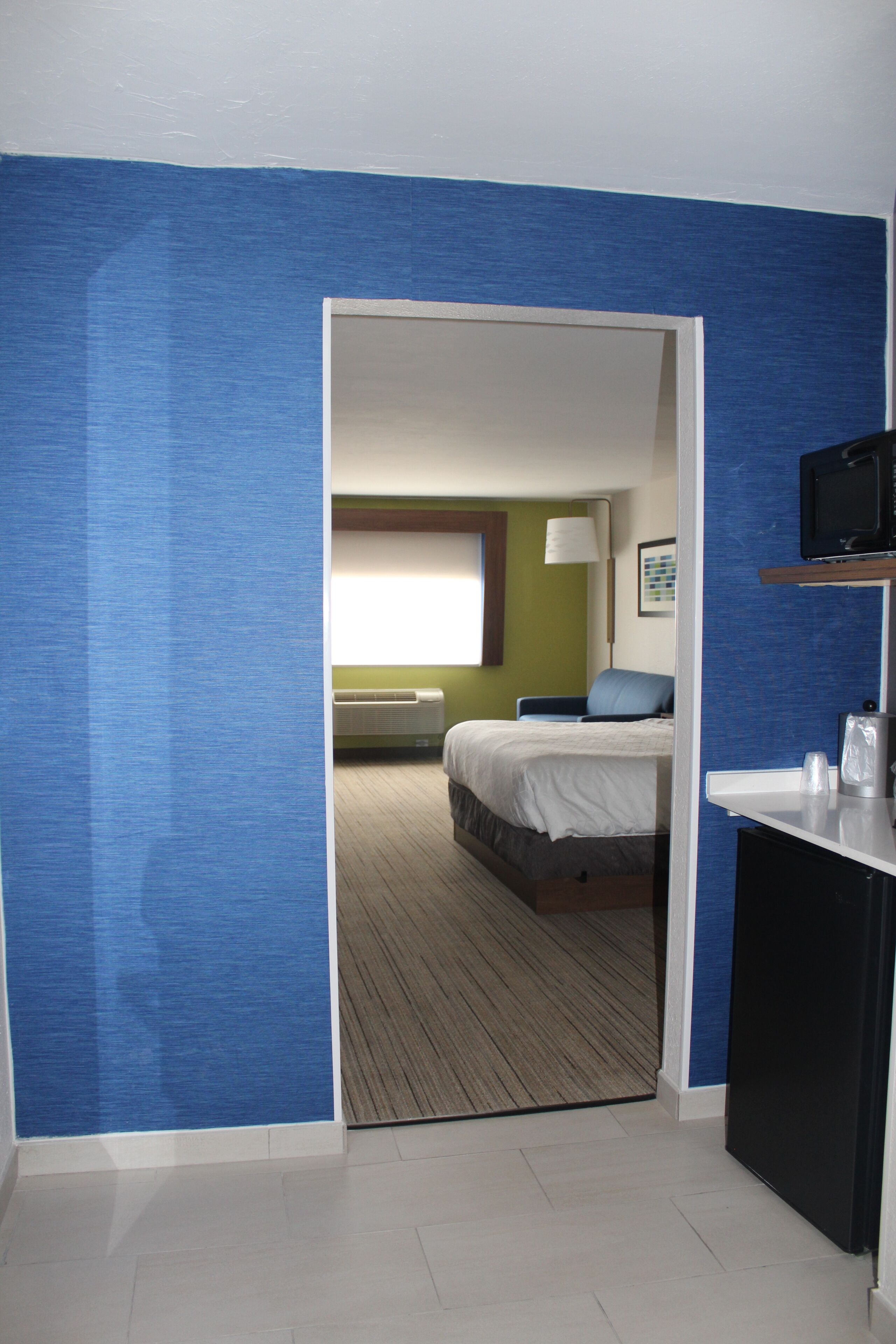 A hotel room with a bed, a desk, and a television.