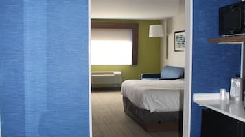 A hotel room with a bed, a desk, and a television.