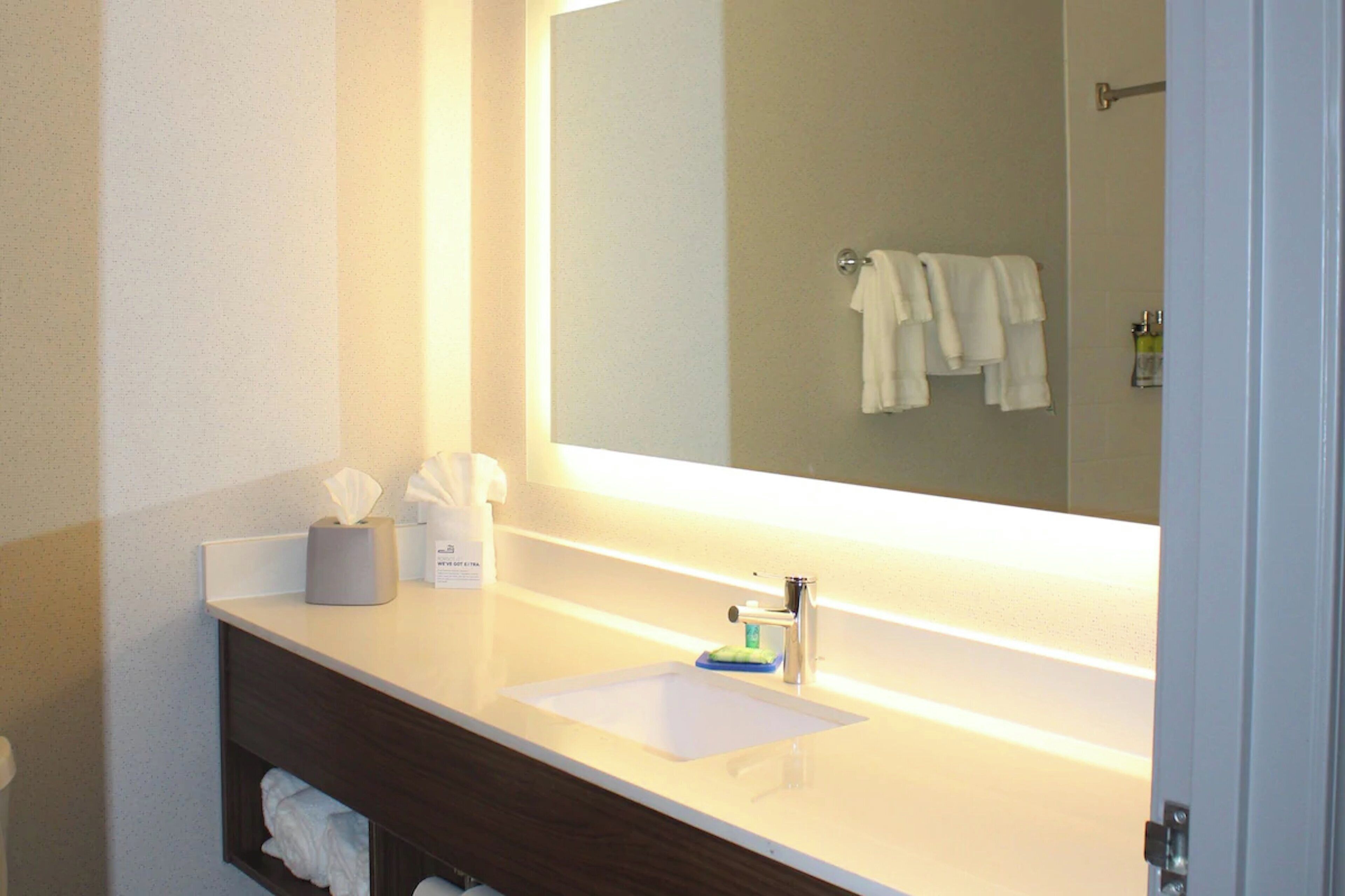 A bathroom with a white sink, a mirror, and a towel rack.