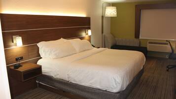 Une chambre d’hôtel avec un grand lit, des tables de chevet, une lampe, une chaise et un écran de projection.
