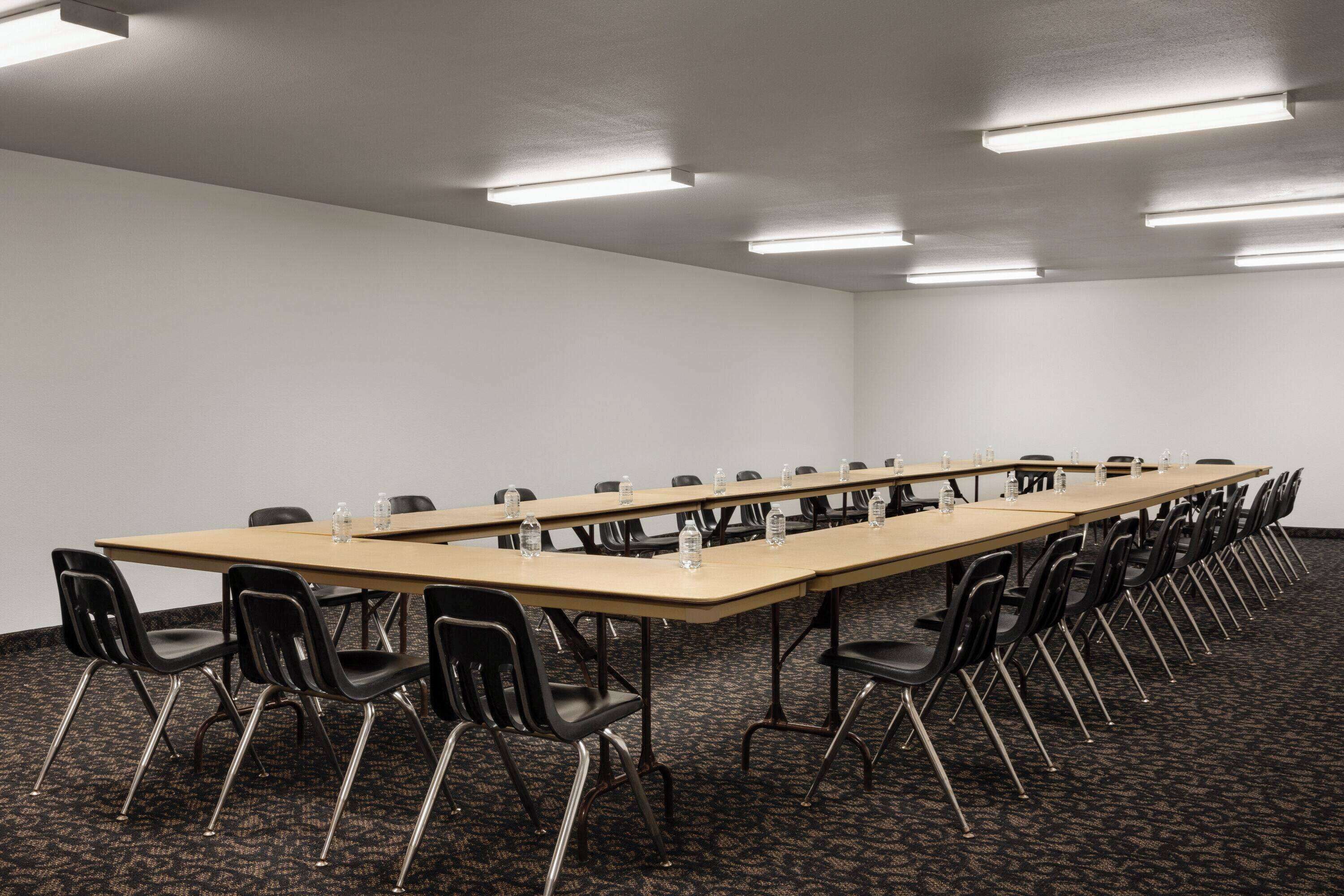 A conference room with a long table, black chairs, and overhead fluorescent lighting.