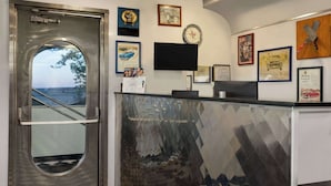 Un área de recepción con diseño moderno, que incluye un mostrador de recepción, un reloj y varias fotografías enmarcadas en la pared.