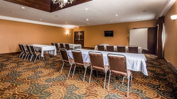 Une salle de conférence équipée de tables et de chaises, d’un tableau blanc et d’un écran de projection.
