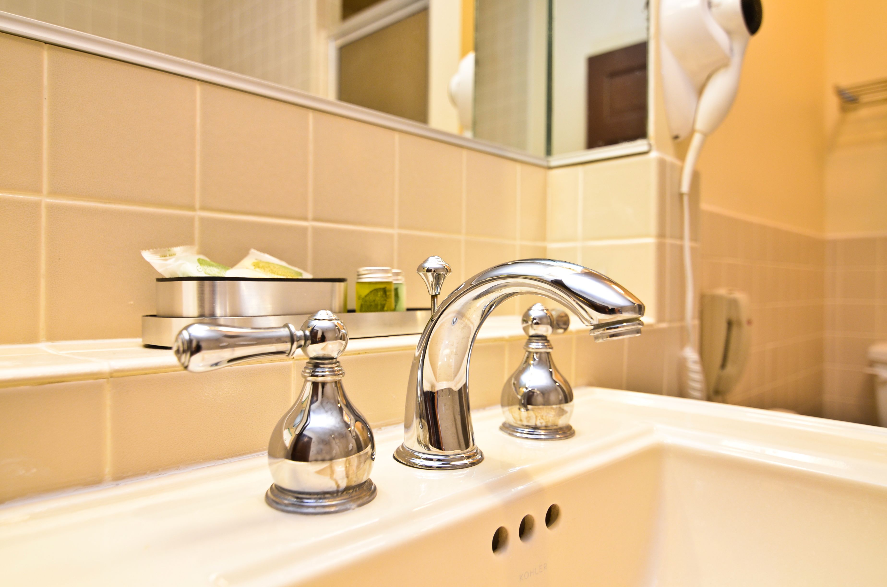 A bathroom with a white sink, two chrome faucets, and a mirror above.