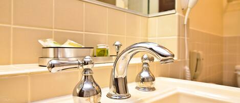 A bathroom with a white sink, two chrome faucets, and a mirror above.