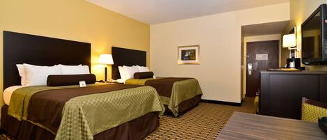A hotel room with two beds, a desk, a chair, a television, and a door.