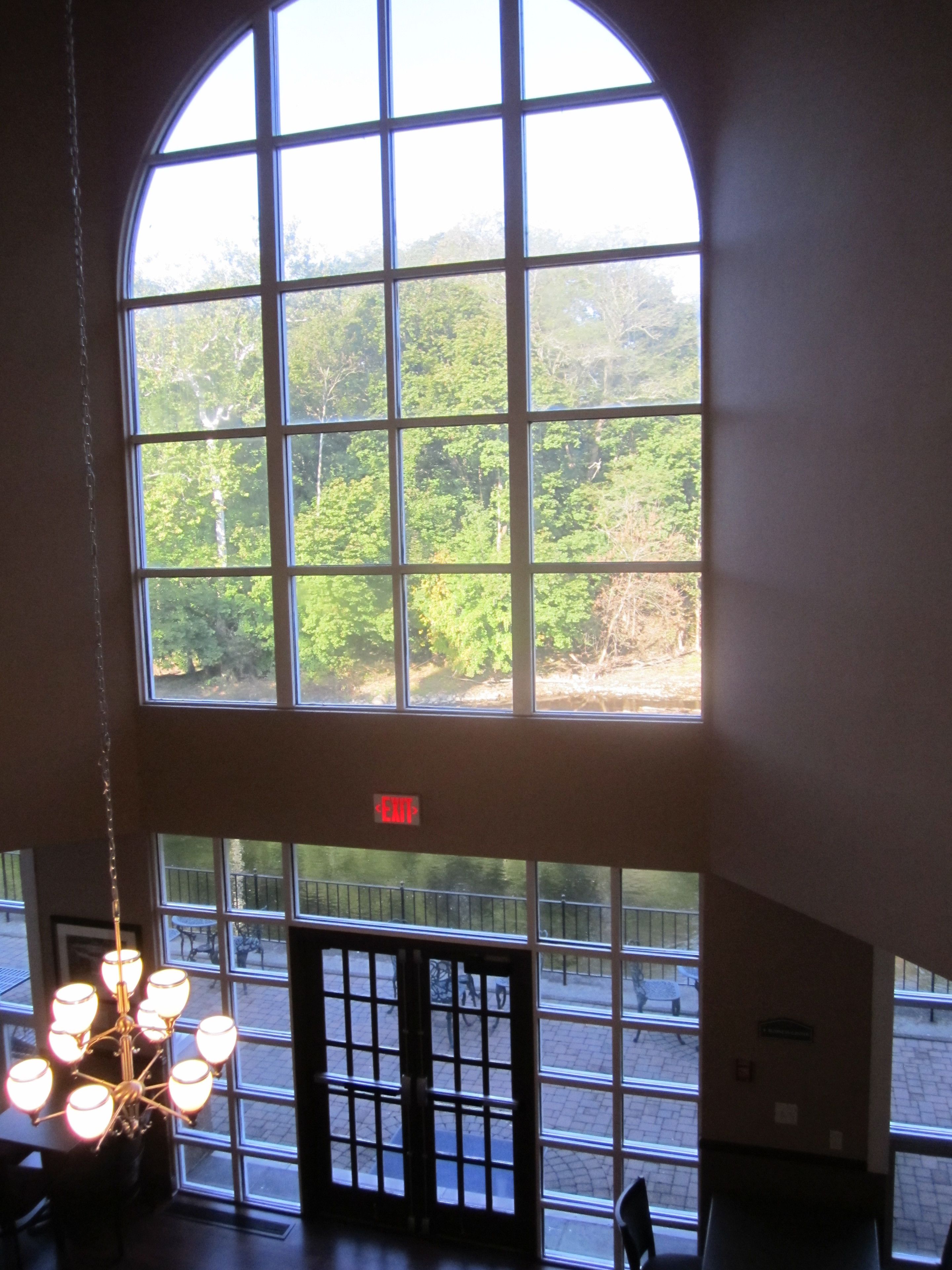 A room with a large arched window overlooking a forested area.