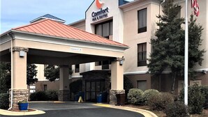 Un hôtel Comfort Inn & Suites doté d’un espace extérieur couvert, d’un drapeau et offrant une vue sur un ciel dégagé.