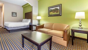 Une chambre d’hôtel avec un lit, un canapé, une table et une lampe.