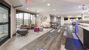 Un hall d’hôtel moderne, doté d’espaces aménagés avec des sièges, d’un comptoir de réception et d’un panneau indiquant clairement la sortie.