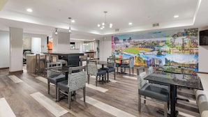 Un hall d’hôtel moderne avec un bar, des tables et des chaises pour prendre un repas.