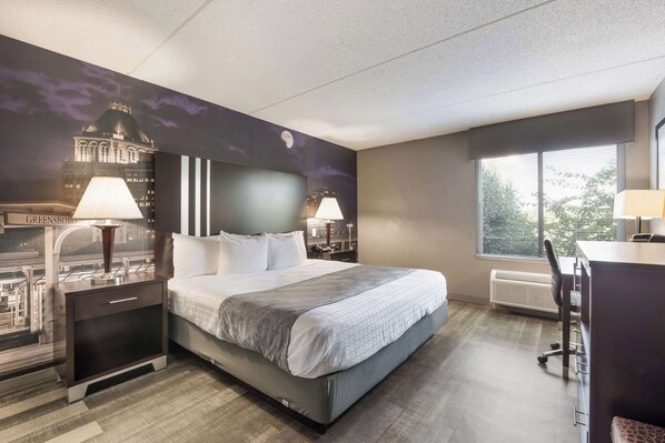 Habitación de hotel con una cama grande, dos mesitas de noche con lámparas, un escritorio con una silla y una ventana con persianas.
