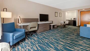 Une chambre d’hôtel équipée d’un bureau, d’une chaise, d’une télévision et d’un canapé bleu.