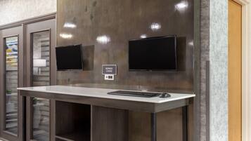 A business center with a desk, two monitors, and a sign indicating the location.