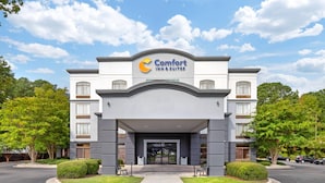 L’entrée d’un hôtel Comfort Inn & Suites, avec une façade moderne, de grandes portes vitrées et un ciel dégagé.