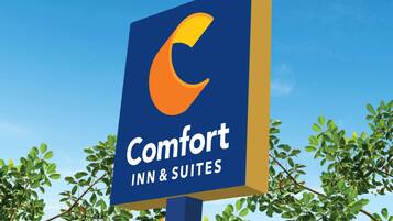 A sign for Comfort Inn & Suites with a blue background and a stylized orange 'C'.