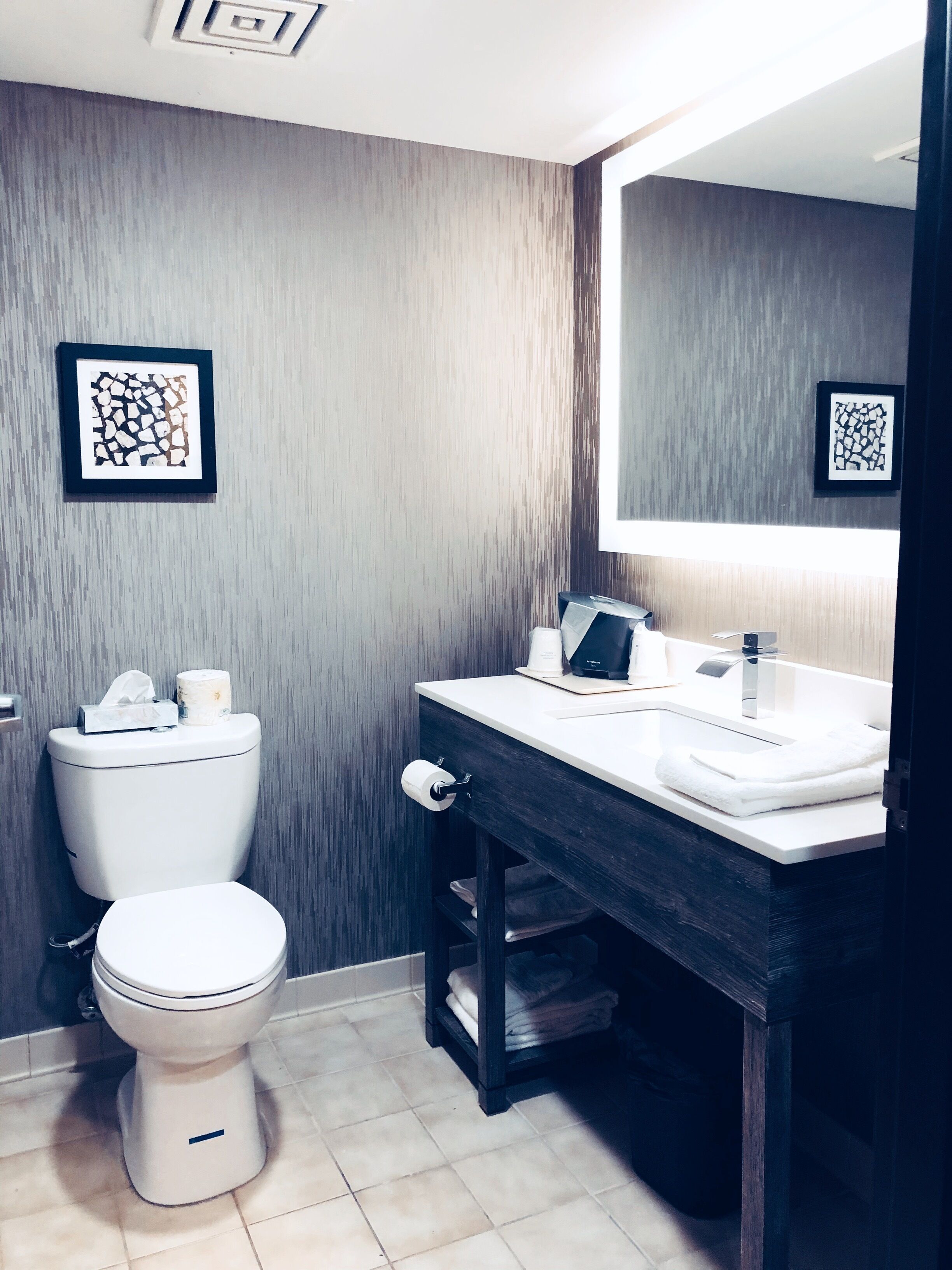 Un baño moderno con inodoro, lavamanos y espejo.