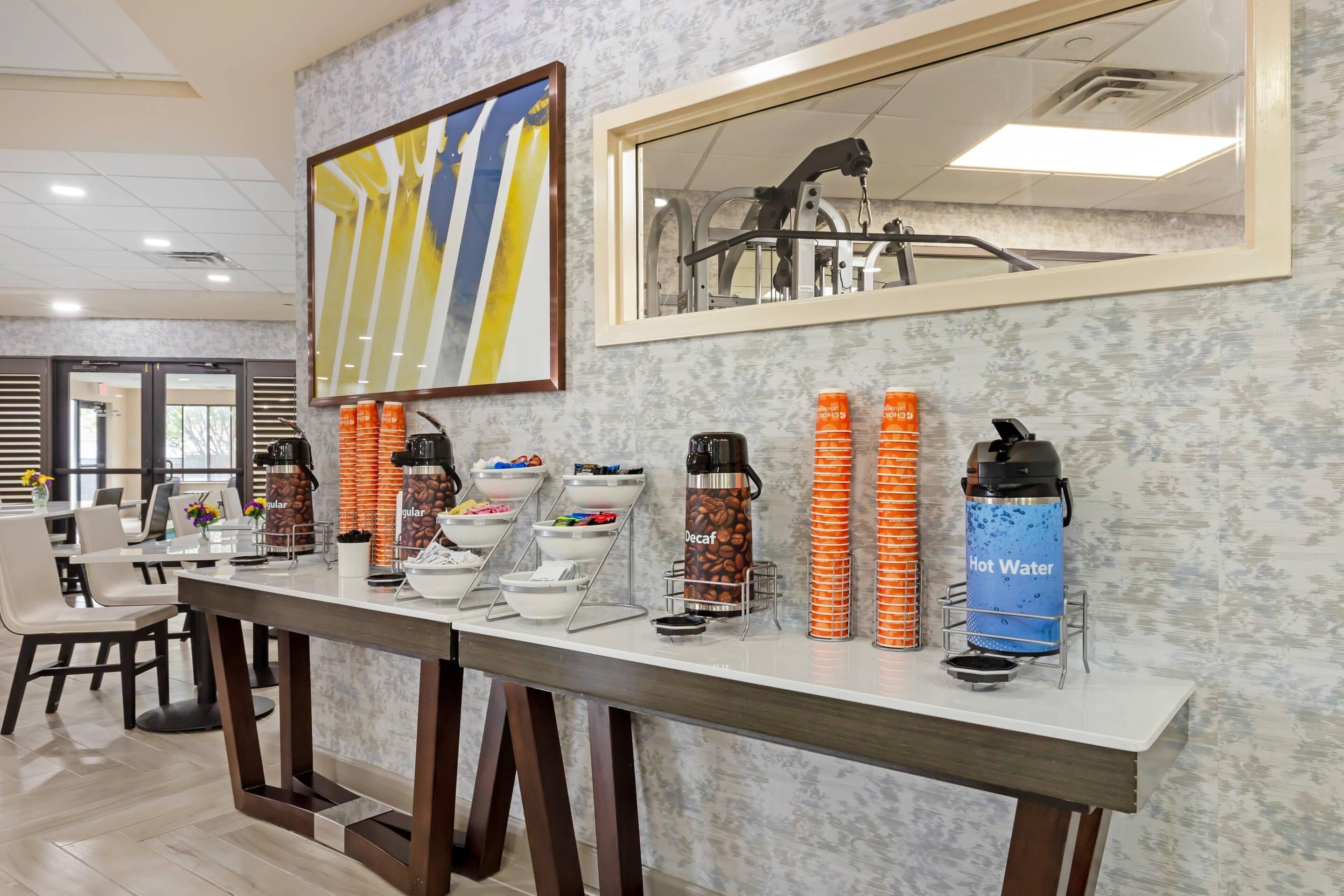 A breakfast bar with coffee dispensers, orange cones, and a hot water dispenser.