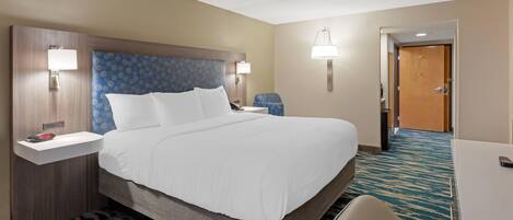 Ein Hotelzimmer mit einem großen Bett, Nachttischen, einem Schreibtisch und einem Sessel.