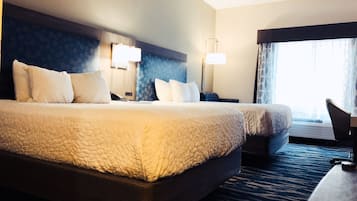 A large bed with a headboard, two bedside tables, a desk, and a chair in a hotel room.
