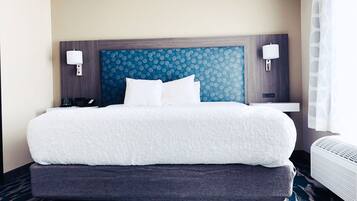 A hotel room with a large bed, a headboard with a blue patterned design, two bedside tables with lamps, and a carpeted floor.