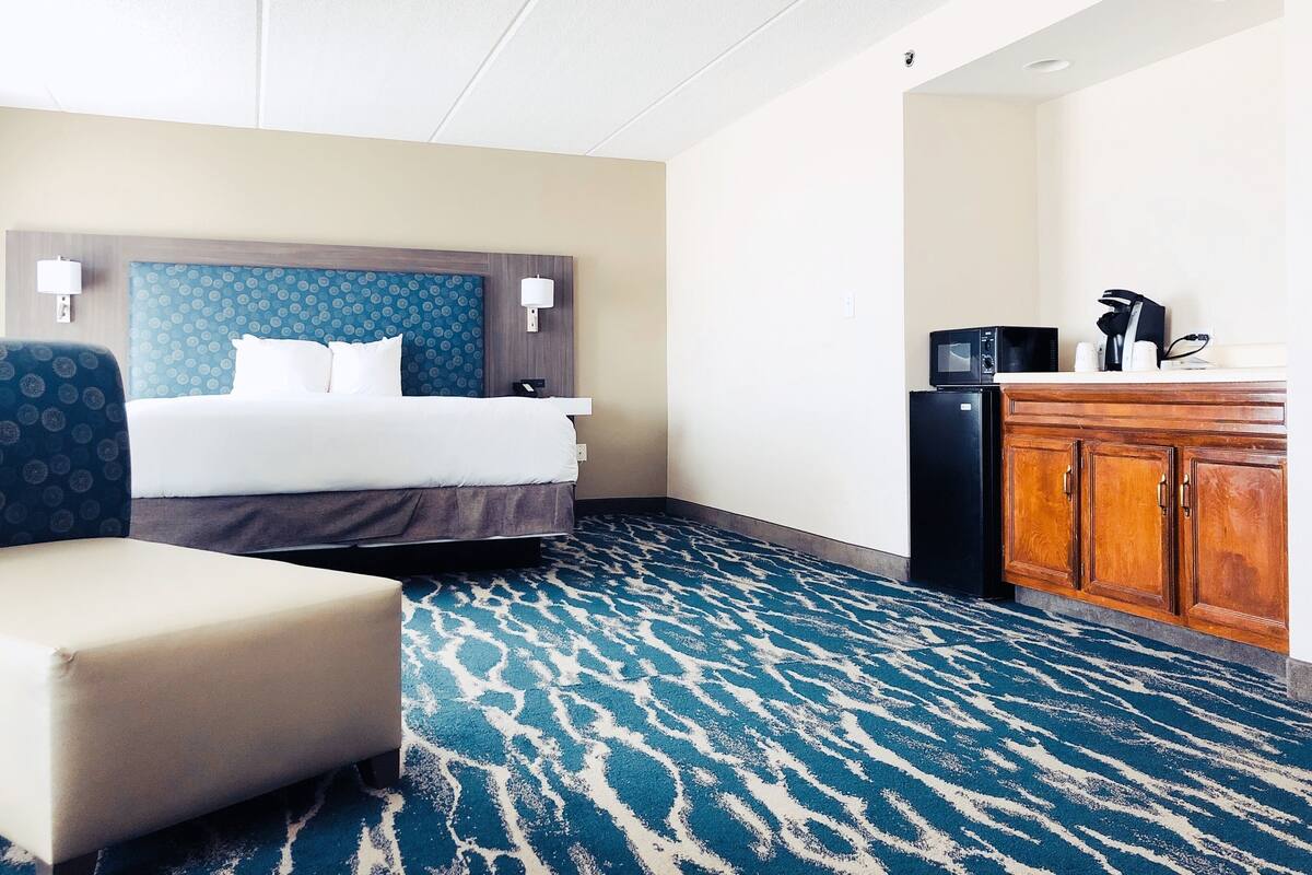 Une chambre d’hôtel équipée d’un lit, d’un bureau, d’une chaise, d’un four à micro-ondes et d’un réfrigérateur.