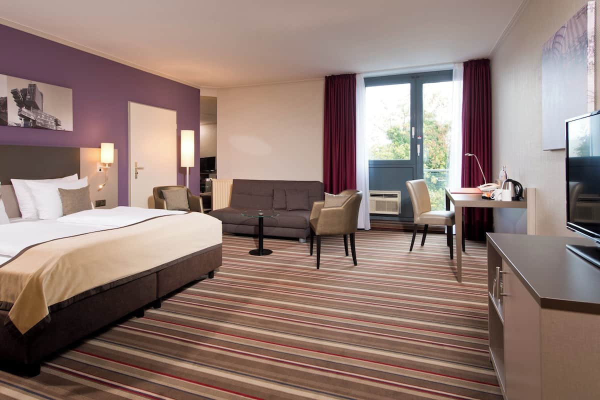 Una habitación de hotel con cama, sofá, escritorio y televisión.