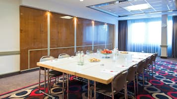 A conference room with a long table, chairs, and a clock on the wall.