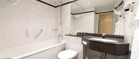 A modern bathroom with a bathtub, toilet, sink, and a large mirror.