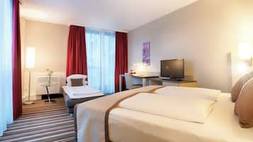 A hotel room with two beds, a desk, a chair, a TV, and a lamp.