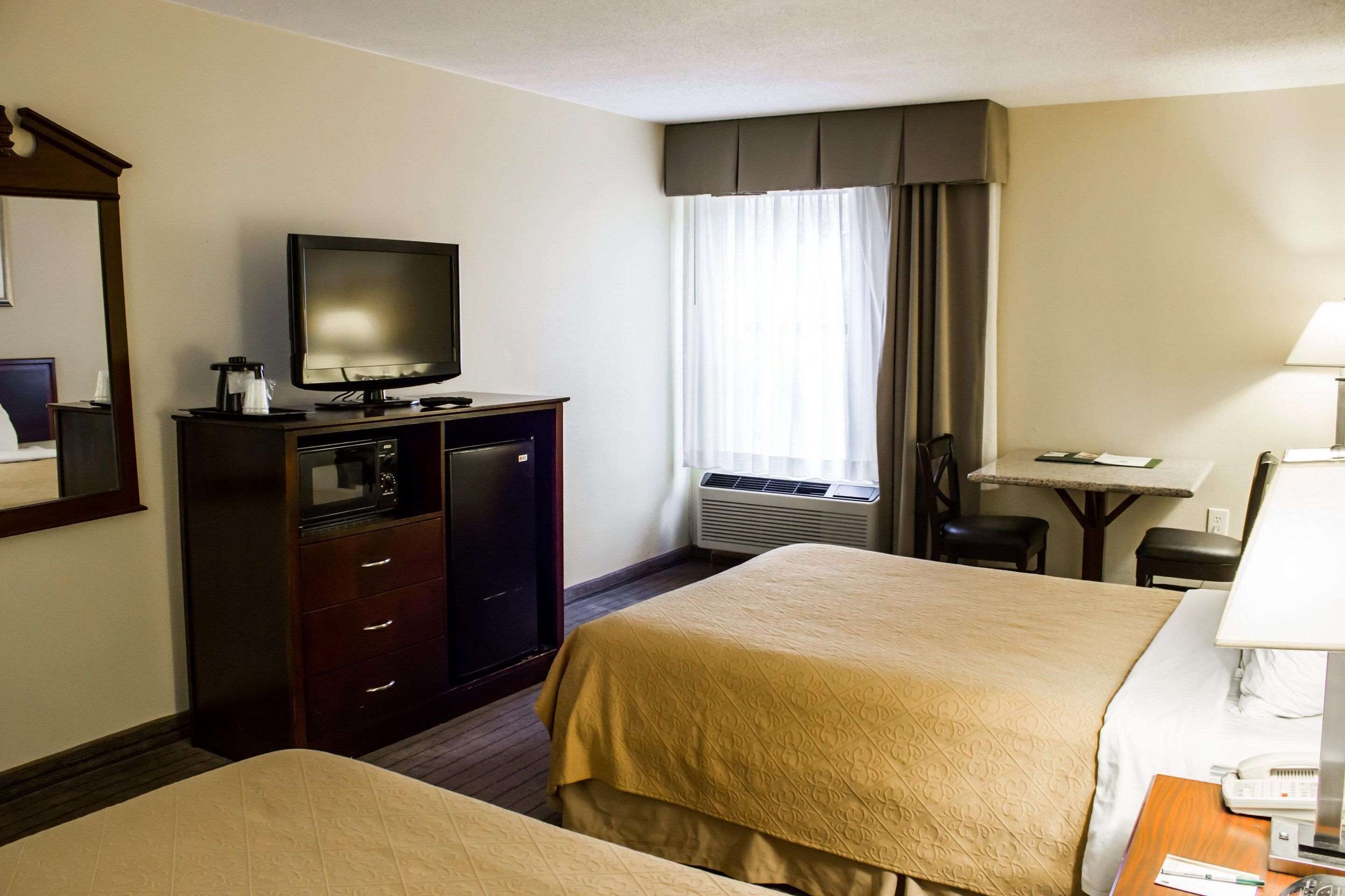 Habitaci ón de hotel con dos camas, un televisor, un escritorio y una silla.
