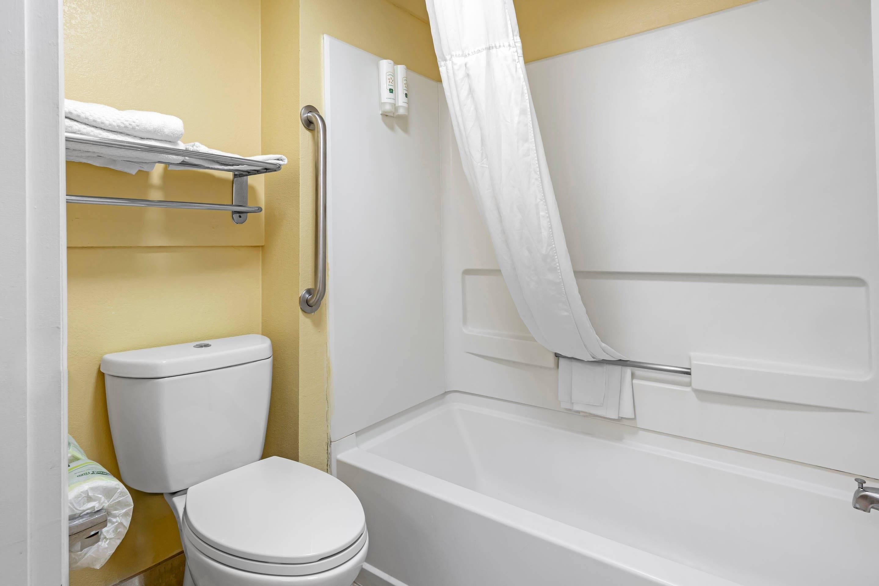 Ein Badezimmer mit Toilette, Duschvorhang und Handtuchhalter.