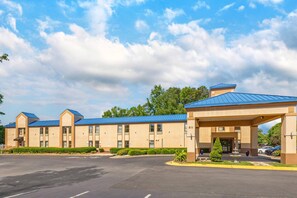 A hotel with a blue roof, multiple rooms, and a parking lot.