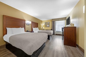A hotel room with two beds, a desk, a TV, and a window with curtains. - Quality Inn Fuquay Varina East (Fuquay-Varina)