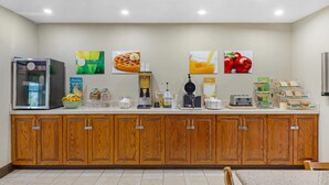 A breakfast bar with a refrigerator, waffle maker, coffee maker, and various food items. - Quality Inn Fuquay Varina East (Fuquay-Varina)